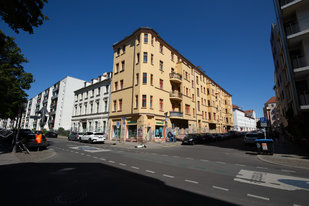 High contrast unedited image with skewed perspective of residential buildings with graffiti and surrounded by parked cars.