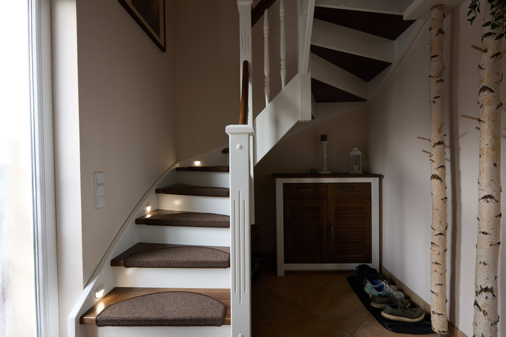 Unedited image of a dimly lit and cluttered spiral staircase with incorporated spotlights.