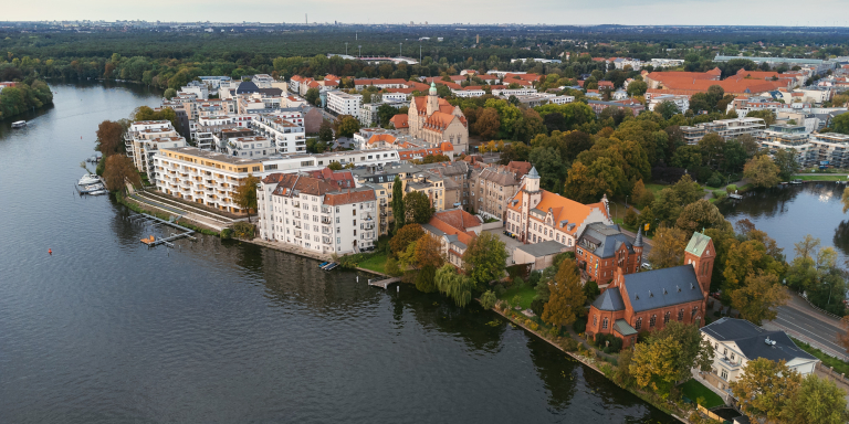 Aerial view of a part of Köpenick, Berlin by a river, with historic buildings and lush greenery.