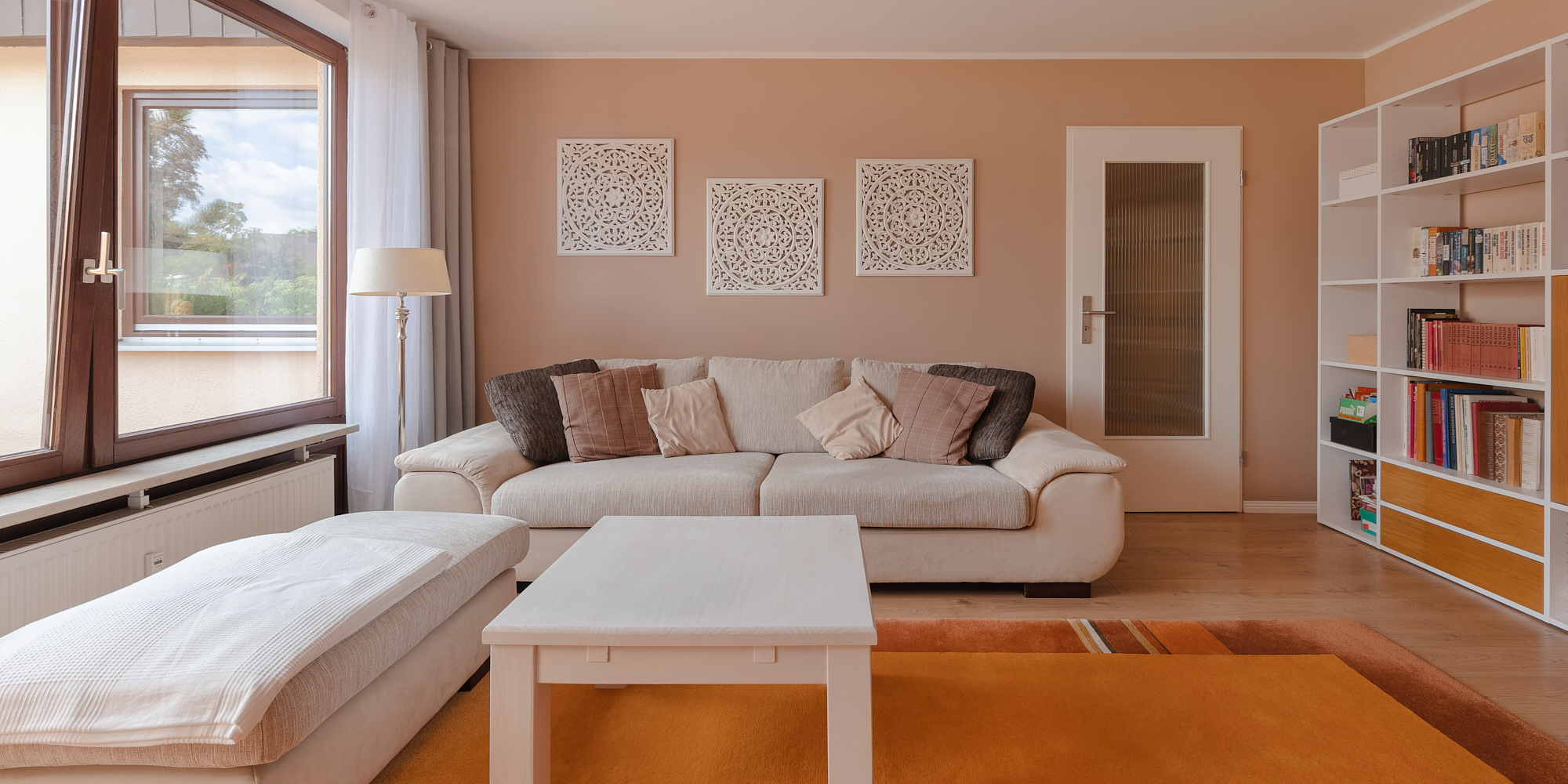 Cozy living room with contemporary furniture, wooden floors, and large windows overlooking a garden.