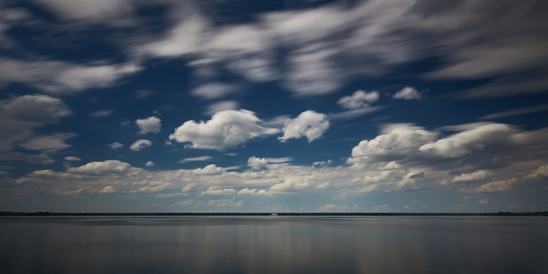 Langzeitbelichtung eines offenen Himmels mit vereinzelten Wolken, die verschiedene Wolkenarten an einem klaren Tag hervorhebt.