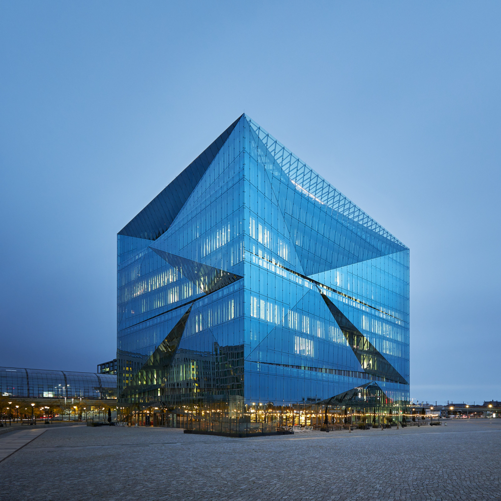 Langzeitbelichtung des 3XN Cube Berlin mit eingeschalteter Innen- und Straßenbeleuchtung bei Sonnenaufgang.