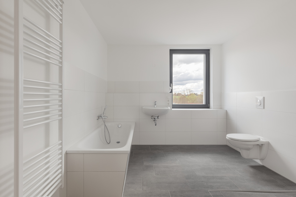 Large accessible bathroom with big window in monochromatic tones.