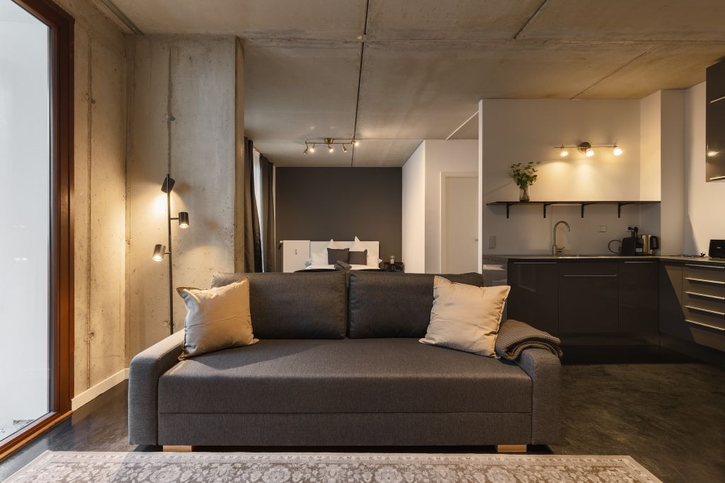 Open space apartment with unfinished walls, dark flooring and furniture in Mitte, Berlin.