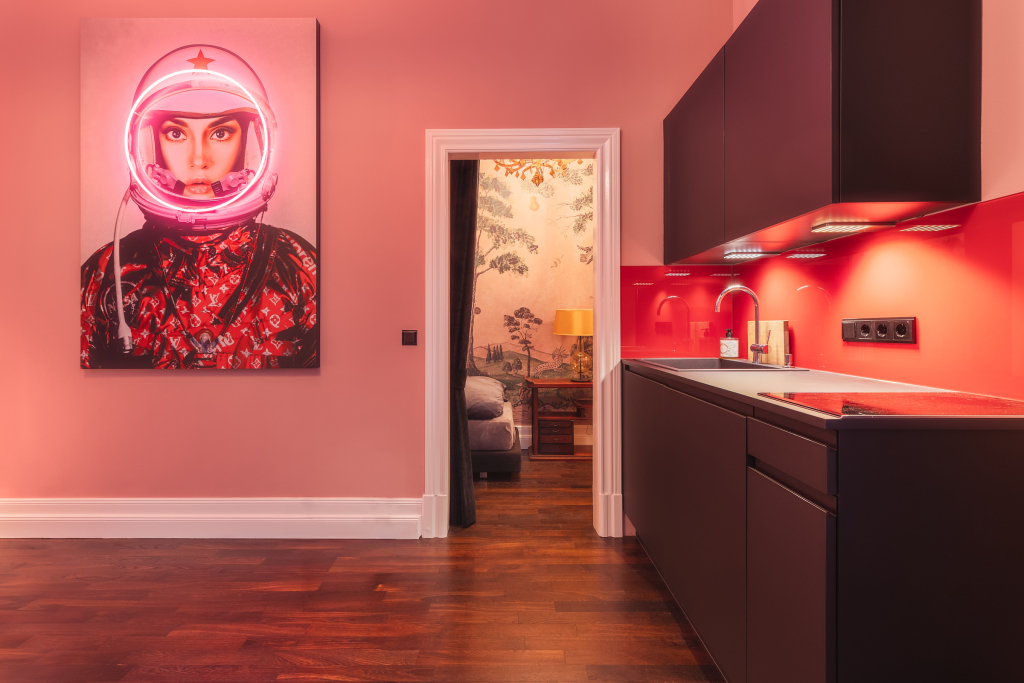 Small open space red kitchen with dark cabinets and a large neon painting in Charlottenburg, Berlin.