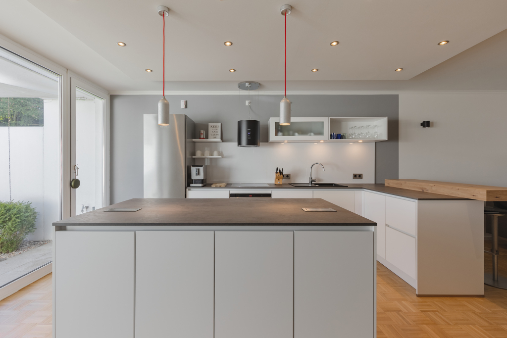 Open space kitchen with an island, decorated with gray and white elements in Zehlendorf, Berlin.