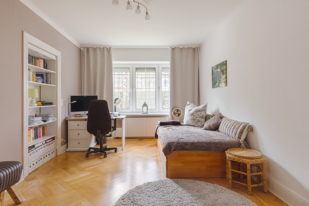 Bright bedroom with incorporated bookshelves and a small study corner near Pankow, Berlin.