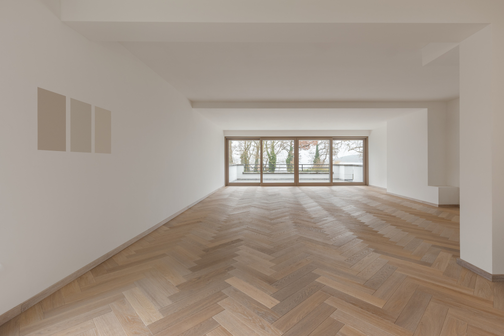 Interior of a spacious empty room with large windows that leads to a large balcony in an under construction villa.