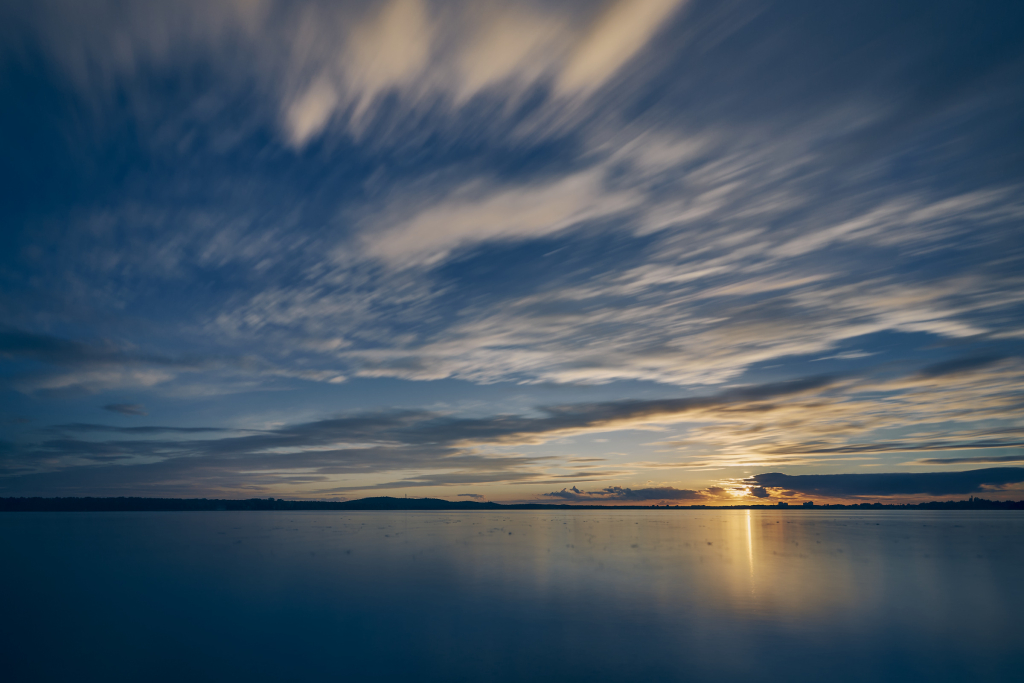 Langbelichtete Wasserlandschaft eines Sonnenuntergangs mit ausklingenden Bewegungen der einheimischen Vögel am Großen Müggelsee, Köpenick.