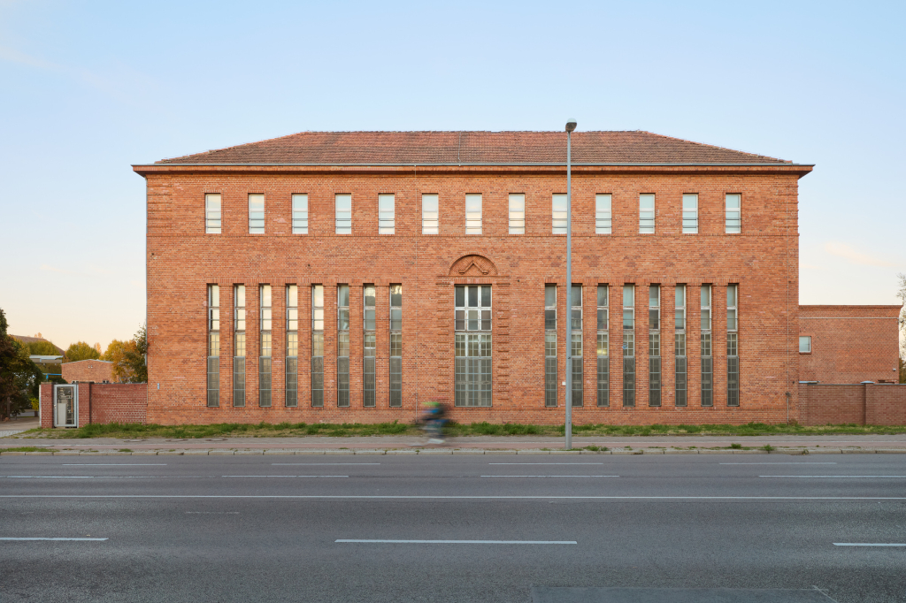 Red brick building near Rummelsburg, Berlin with tall, narrow windows and minimalist design, showcasing industrial aesthetics and functional, symmetrical form.