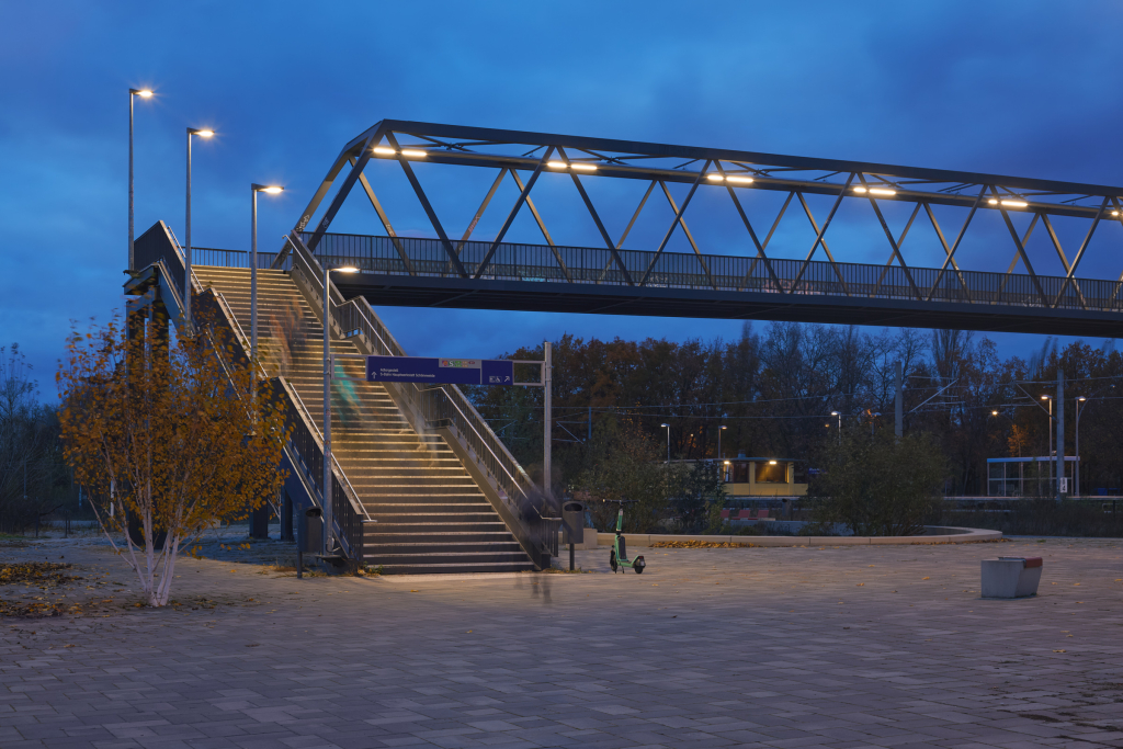 Illuminated pedestrian bridge and stairs in Johannisthal, Berlin, during the blue hour.