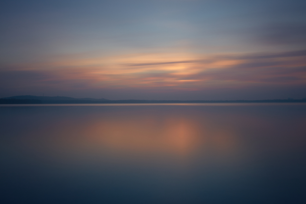 3-minute long exposure over the Großer Müggelsee in Köpenick, Berlin, at sunset with pastel pink and orange hues reflected in the water.