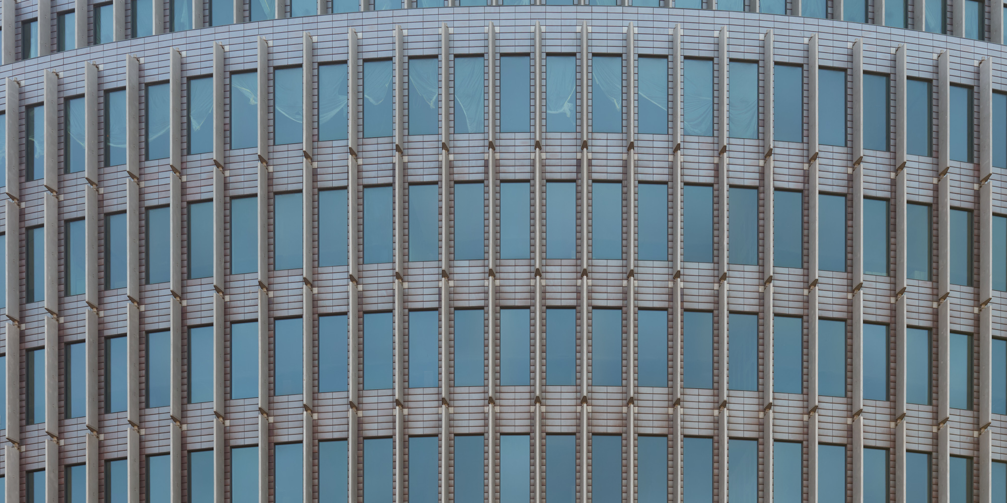 Close-up of a modern office building on the Kurfürstendamm in Berlin, featuring repetitive vertical window patterns.