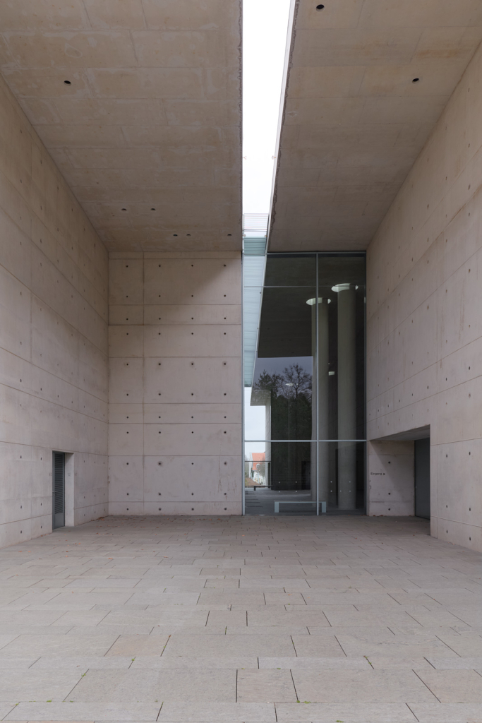 Teil der Rückansicht des Krematoriums Baumschulenweg in Berlin mit großen Fenstern, die einen Blick in das Innere ermöglichen.