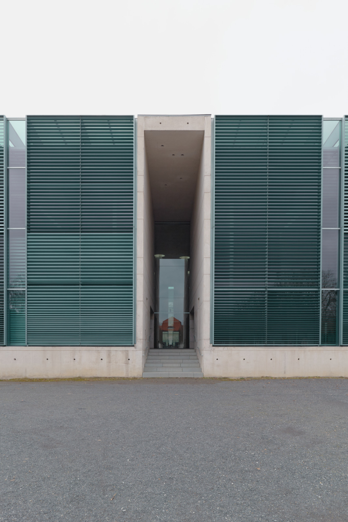 Eingang des Krematoriums Baumschulenweg in Berin, das sich durch ein modernes, schlichtes Design mit großen Glastüren auszeichnet.