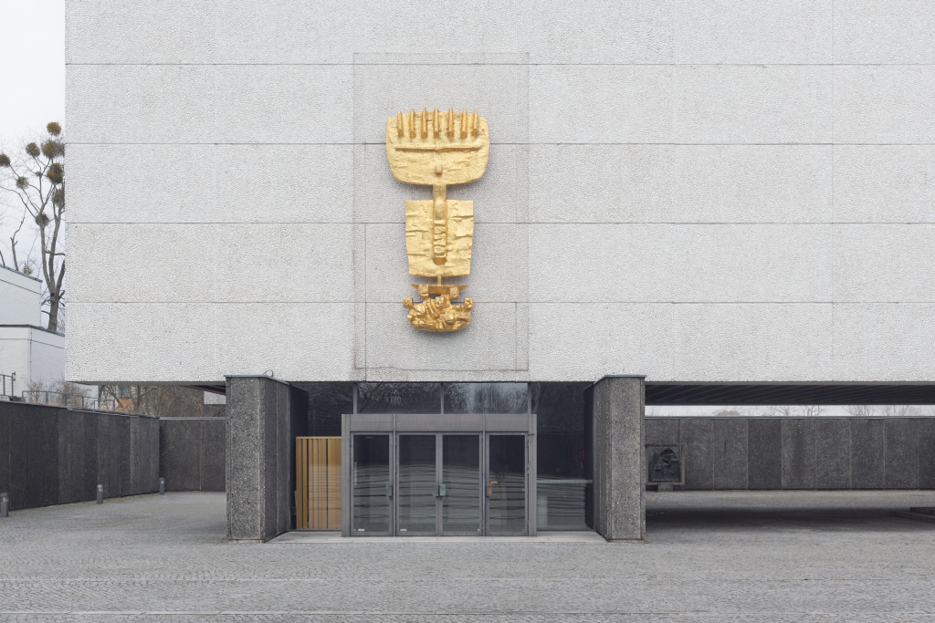 Eingang der Maria Regina Martyrum in Berlin, mit einer goldenen, dekorativen Statue über der Eingangstür.