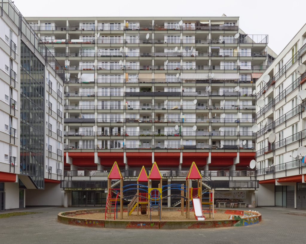 Bild des Pallasseums in Schöneberg, Berlin, mit einem kleinen Spielplatz davor, der seine modernistischen architektonischen Merkmale und seine markante Betonstruktur hervorhebt.