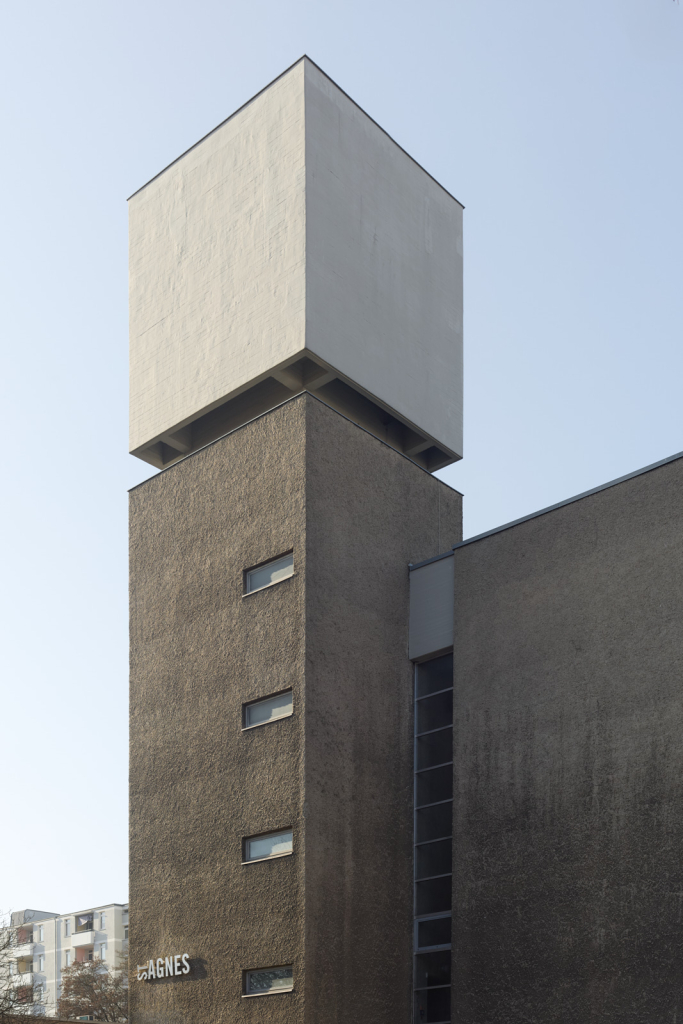 Der Kirchturm der St.-Agnes-Kirche in Berlin-Kreuzberg zeigt sein minimalistisches Design mit klaren Linien und rohen Betonflächen.