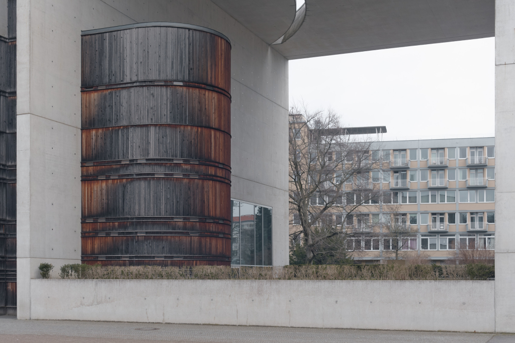 Detaillierte Außenansicht des Altars der St. Canisius-Kirche in Berlin mit einer großen Holzkonstruktion, die von einem monumentalen brutalistischen Bogen eingerahmt wird.