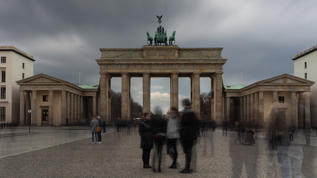 Dynamic contrast of still architecture and moving crowds at Brandenburger Tor, captured in long exposure.