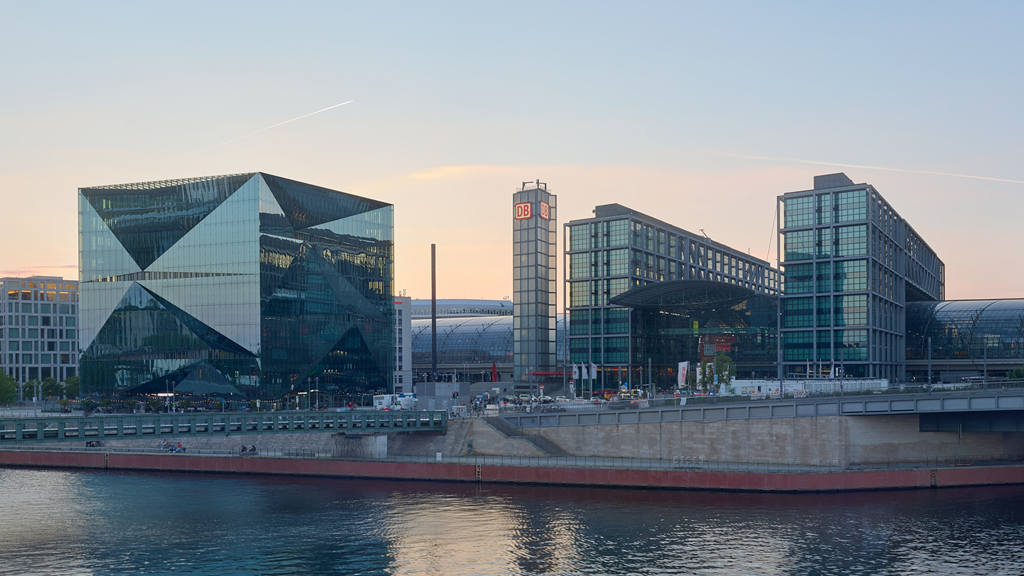 Wide anamorphic shot of Berlin Central Station and 3XN Cube bathed in warm sunset light.