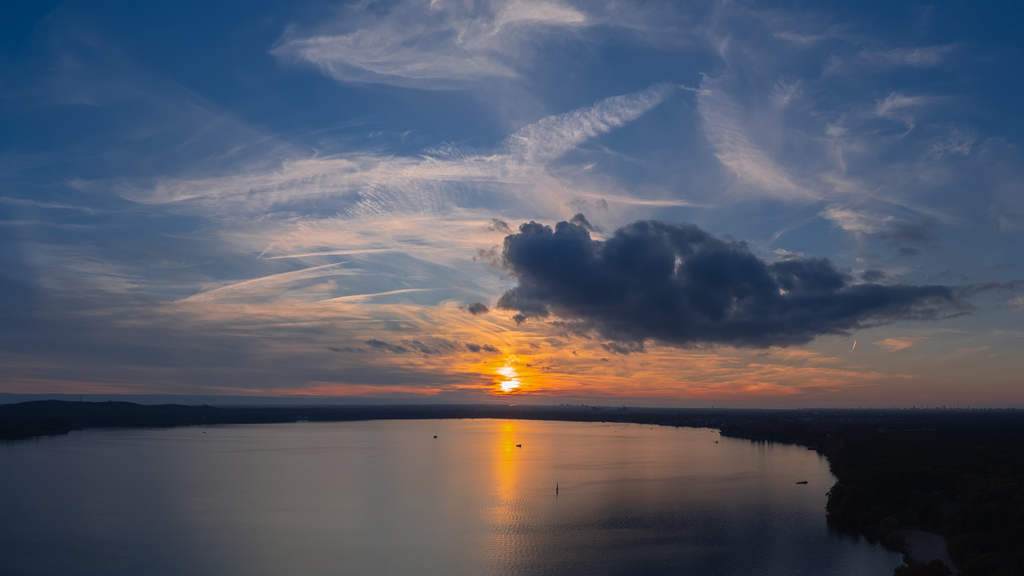 Sunset aerial panorama capturing the glowing sky and calm waters of Großer Müggelsee.