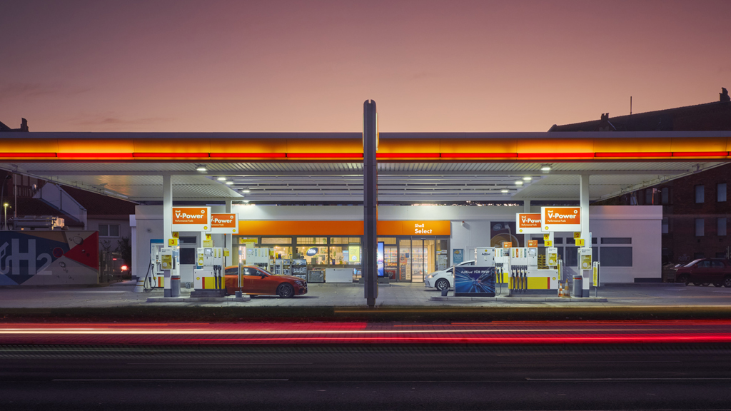 Dusk view of a modern gas station highlighted by vibrant lights and a dramatic colorful sky.