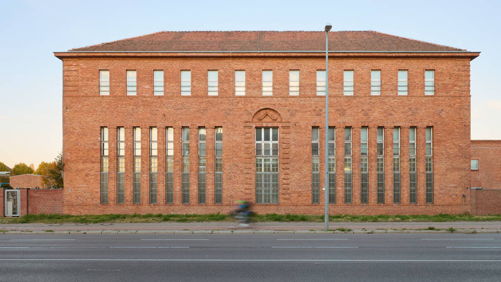 Industrial-style red brick building with symmetrical form and tall windows near Rummelsburg, Berlin.