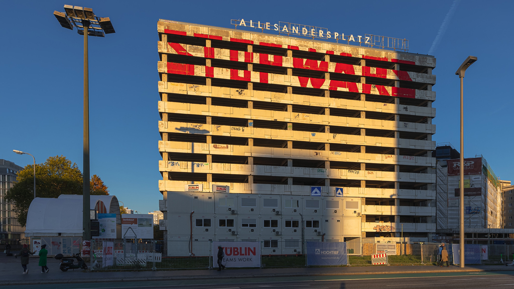Dusk shot of Alexanderplatz in Berlin highlighting a 'Stop Wars' inscription on a public structure.